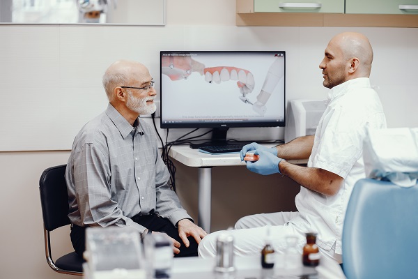 Dentista parla di protesi dentali a un paziente.